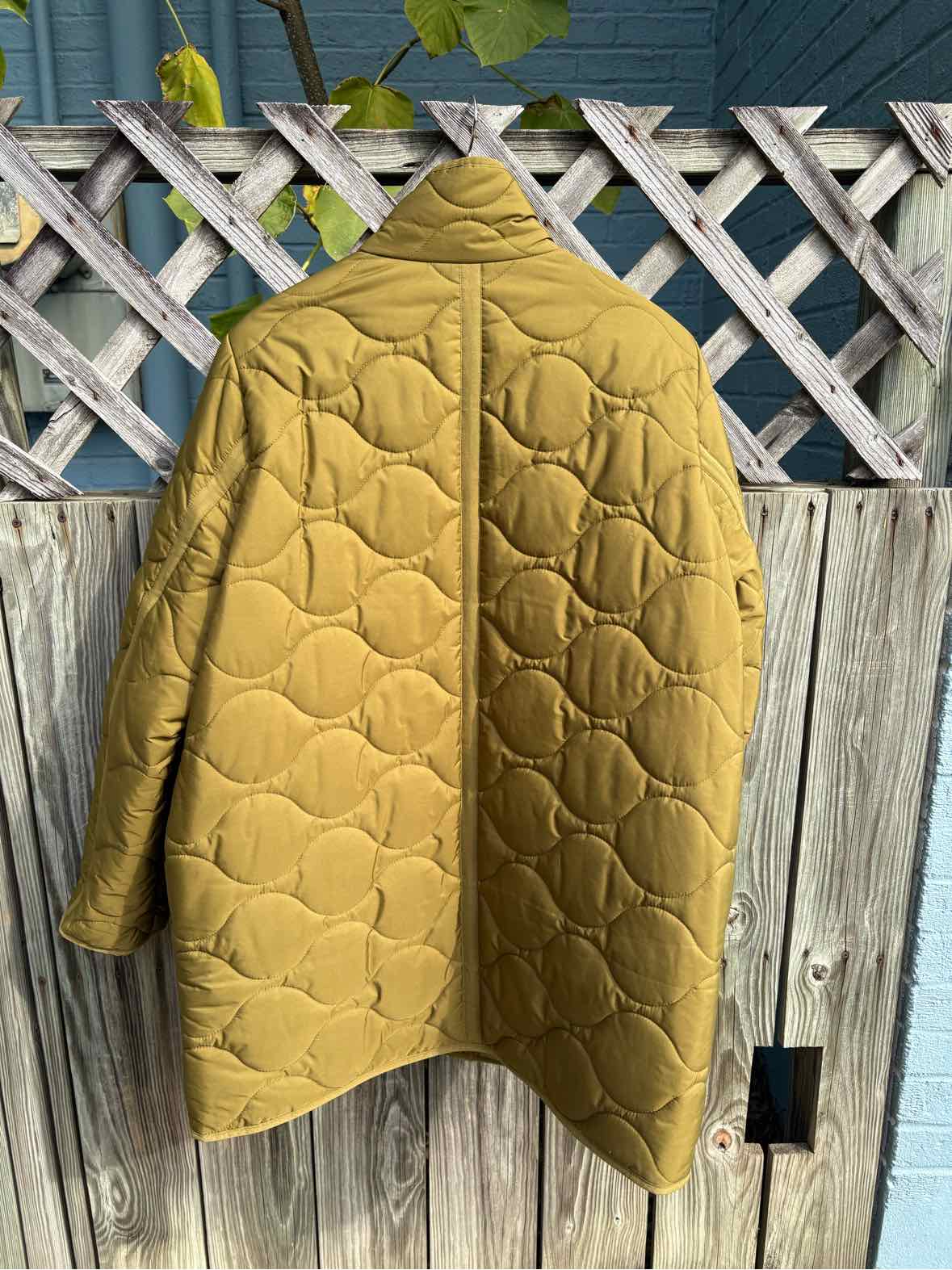 Mustard yellow J.Crew quilted jacket with a high collar, snap front, and rounded stitched pattern.