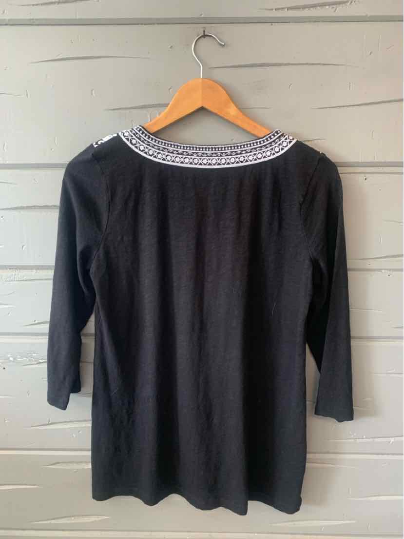 Black long-sleeve top with white embroidered detailing around the rounded neckline.