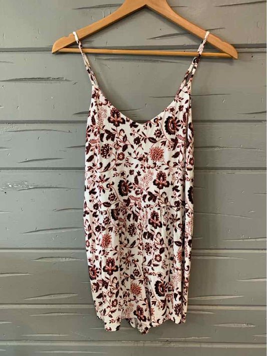 White floral sleeveless mini dress with thin spaghetti straps on wooden hanger.