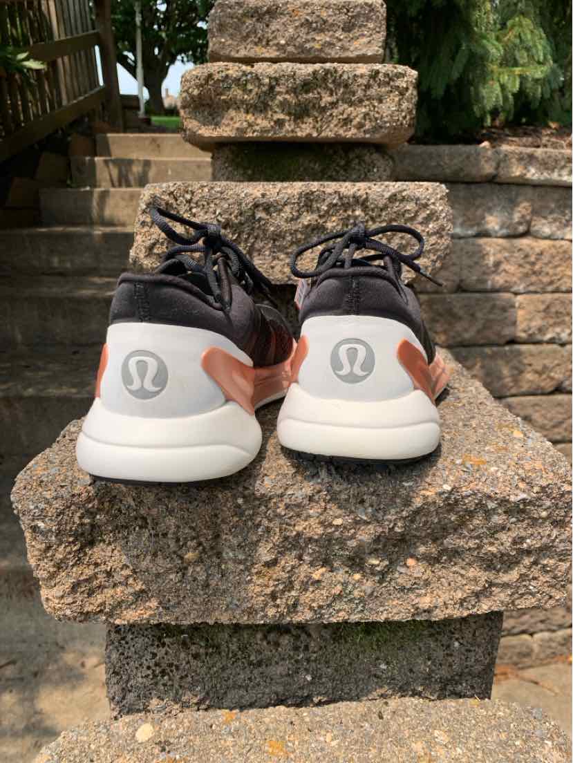 Black and white Lululemon sneakers with rounded heels and pink accent, size 7, rear view.
