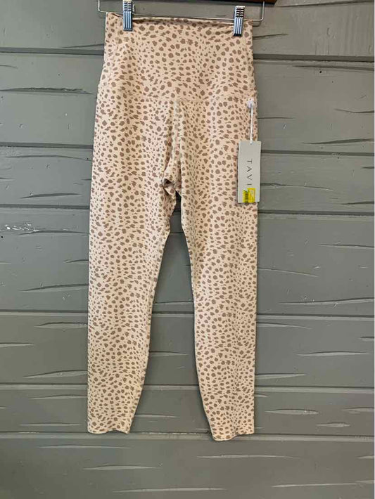 Light pink leggings with small cheetah print pattern and a tag attached, hanging on wooden wall background.