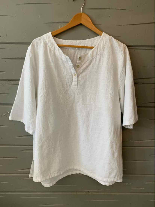 White oversized linen shirt with three-quarter sleeves and a round neckline with a short button placket.