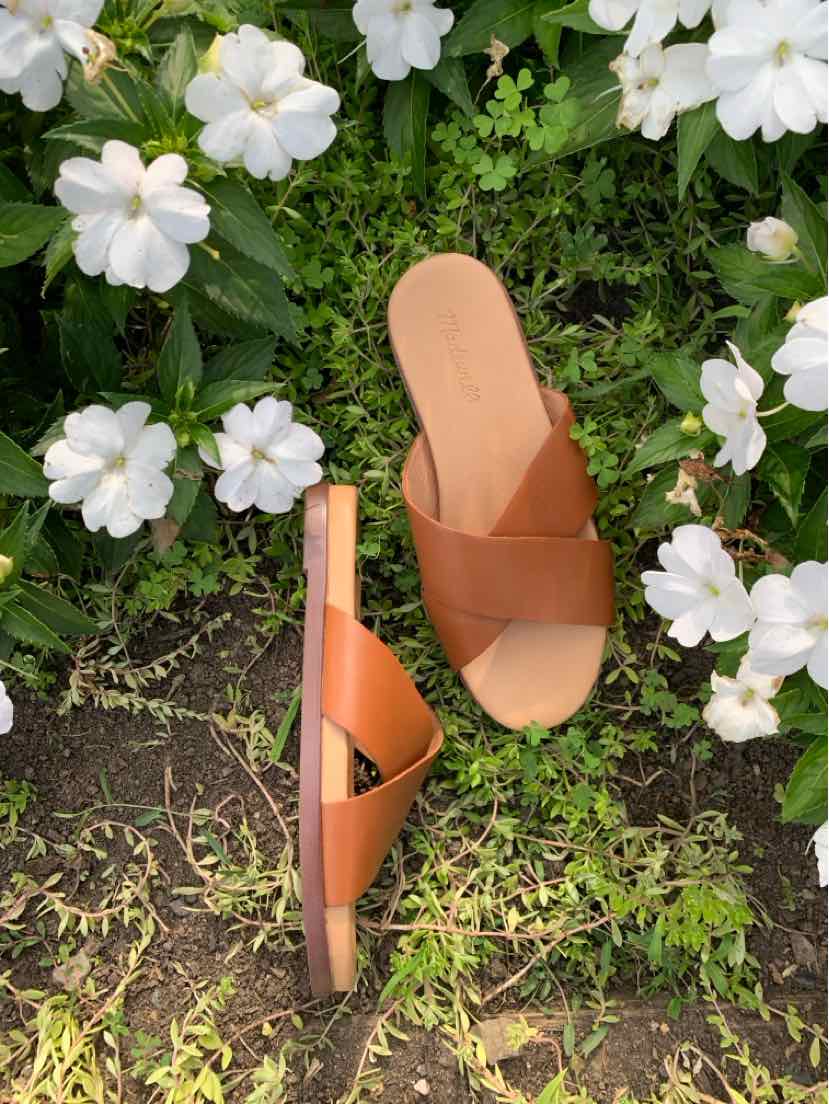 Tan leather slip-on sandal with wide cross straps and flat sole, women's size 8.5.