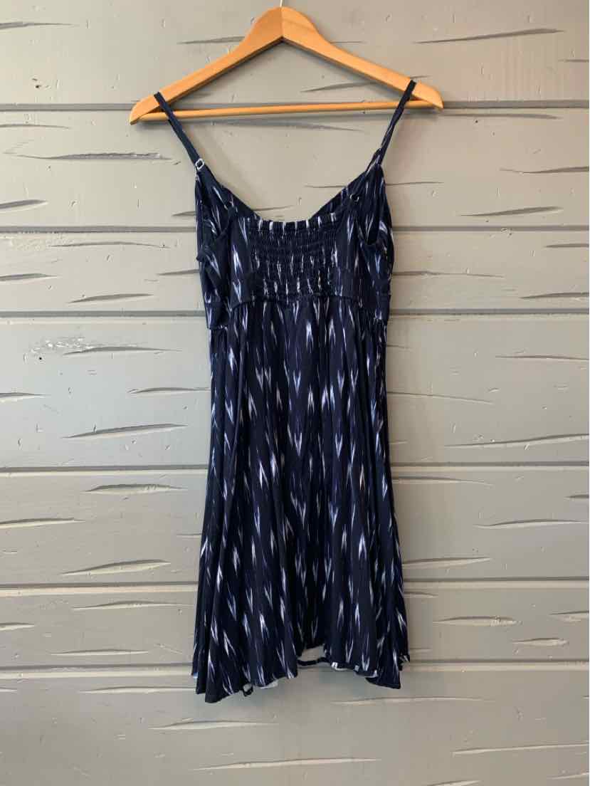Navy blue sleeveless dress with white diamond pattern and spaghetti straps on wooden hanger.