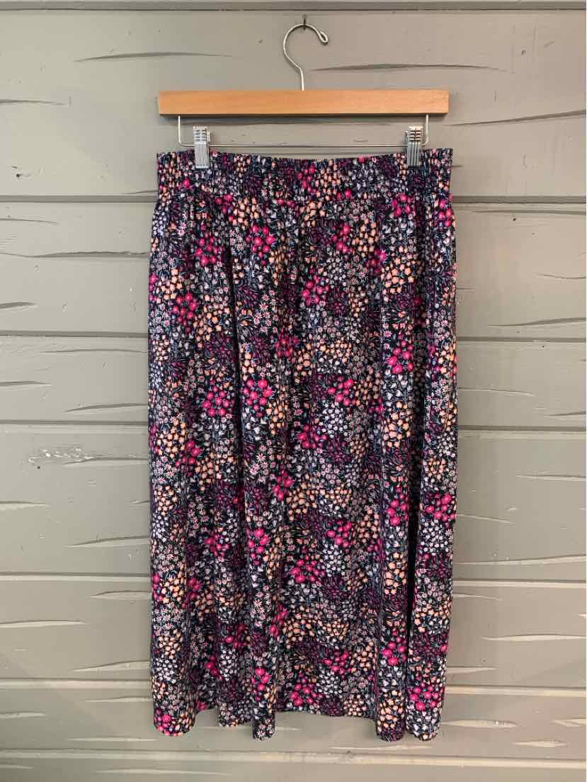 Floral patterned skirt with small pink, purple, and white flowers on dark background, mid-length with waistband and slight.