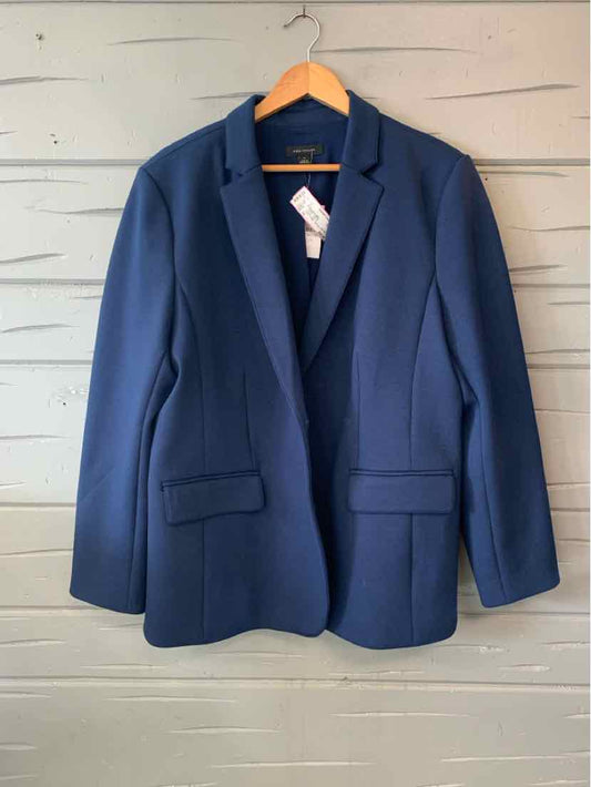 Navy blue tailored blazer with notch lapels, front flap pockets, and structured shoulders hanging on wooden hanger.