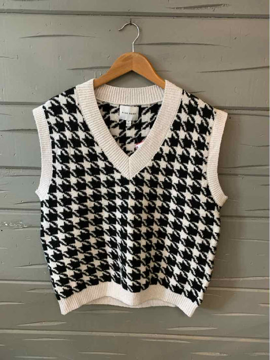 Black and white houndstooth sleeveless sweater vest with white ribbed V-neck and hem, medium size.