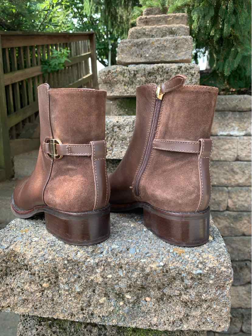 Brown suede ankle boots with side zippers, decorative buckles, and low stacked heels.
