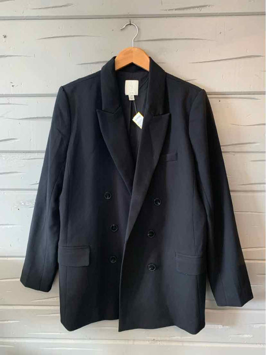 Black double-breasted blazer with notch lapels and front flap pockets, hanging on wooden hanger.
