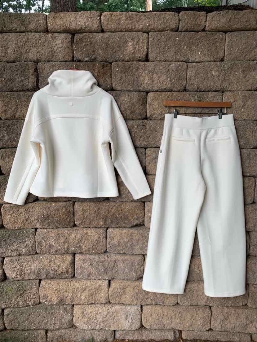 Cream-colored fleece pullover with a high collar and matching wide-leg fleece pants with pockets.