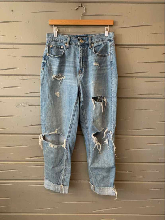 Light blue distressed denim jeans with large rips and frayed hems, size 6.