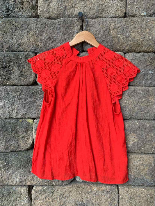 Red dress with scalloped lace sleeves, gathered neckline, and loose fit hanging on wooden hanger.