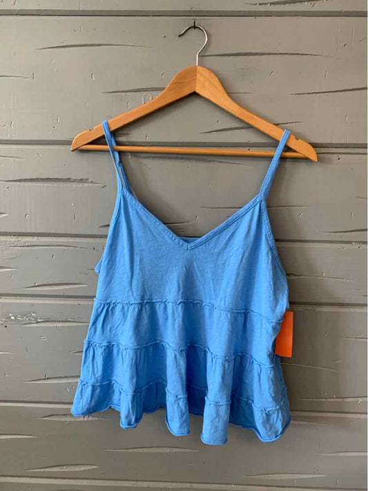Light blue tiered camisole with thin adjustable straps and flowy fabric on wooden hanger.
