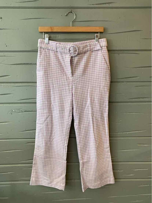 Light pink and white gingham patterned wide-leg pants with belt loops hanging on wooden hanger.