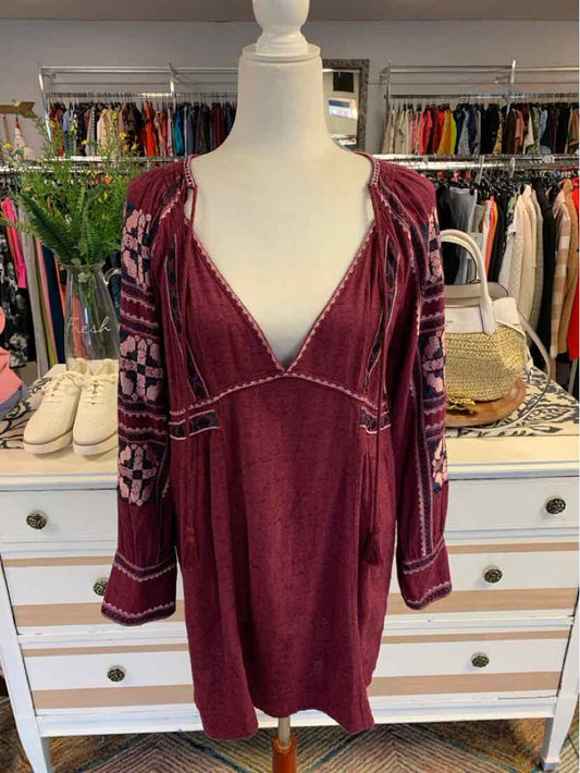 Burgundy long-sleeve mini dress with floral patterned sleeves and V-neckline on mannequin.
