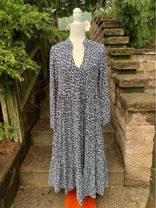 Long black and white polka dot dress with a deep V-neck and three-quarter sleeves displayed on a white mannequin outdoors.