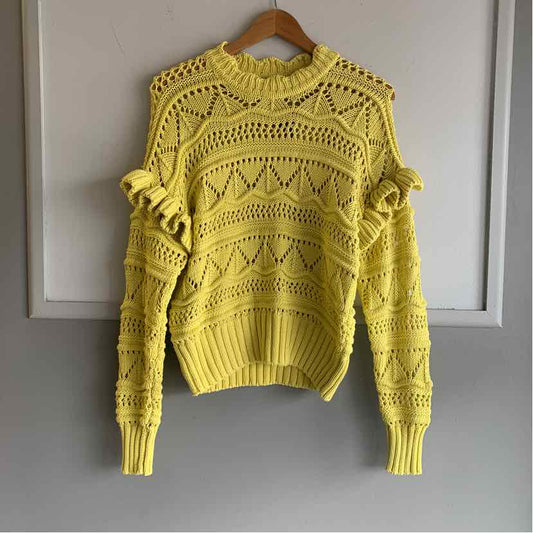 Yellow knitted sweater with ruffled shoulders and geometric openwork pattern.