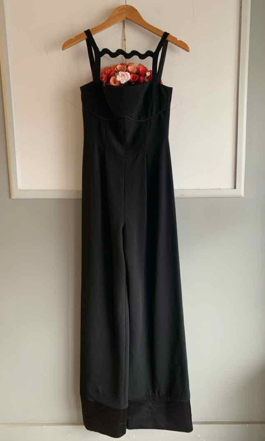 Black wide-leg jumpsuit with floral embroidery on square neckline and thin straps.