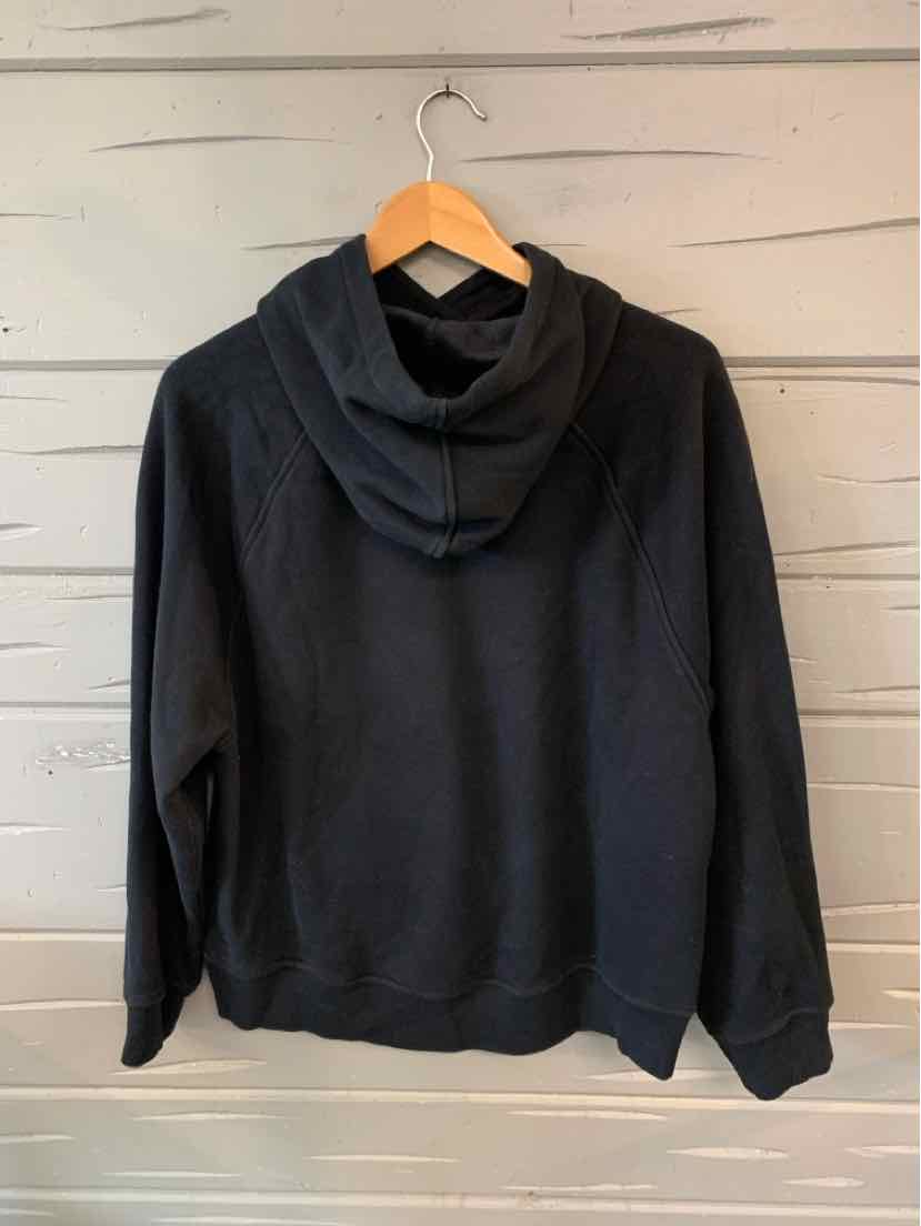 Black hooded sweatshirt with long sleeves and a relaxed fit, displayed on a wooden hanger.