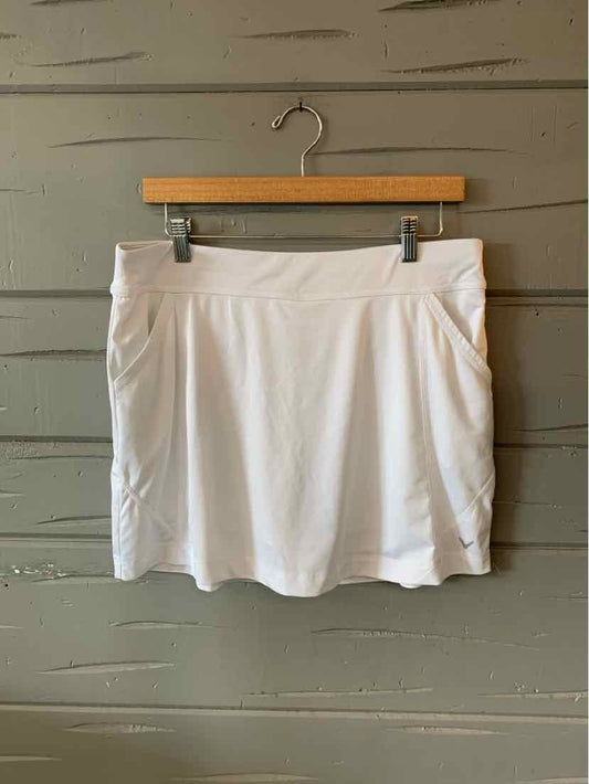 White athletic skirt with subtle pleats, elastic waistband, and smooth fabric hanging on wooden hanger.