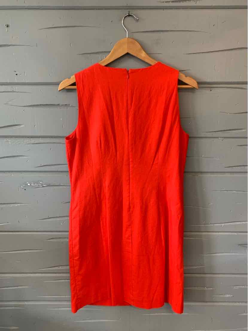 Sleeveless bright red knee-length dress with a fitted silhouette hanging on a wooden hanger.