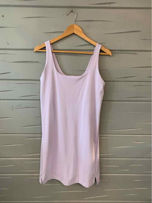 Light lavender sleeveless dress with scoop neck and straight hem on wooden hanger against gray wooden wall.