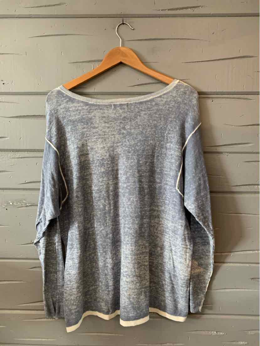 Light blue oversized knit sweater with dropped shoulders and white trim on cuffs and hem.