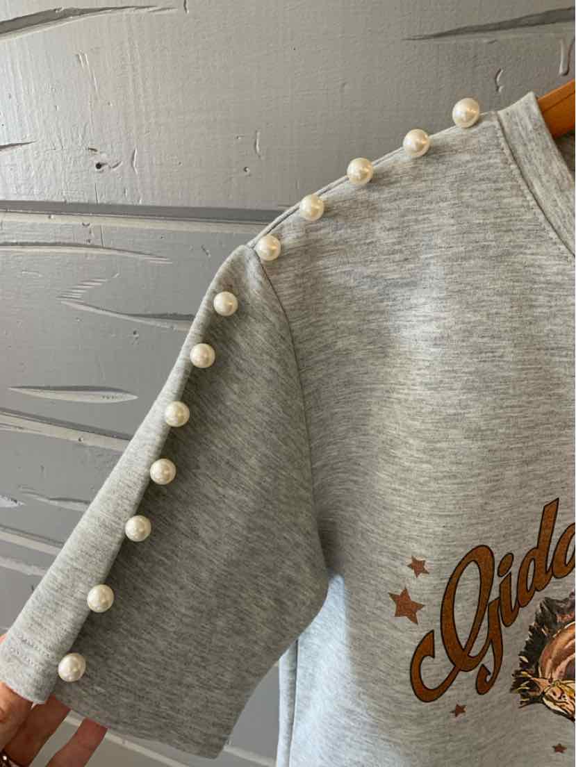 Gray short-sleeve sweatshirt with pearl-like beads along shoulder and sleeve seam, brown graphic text on front.