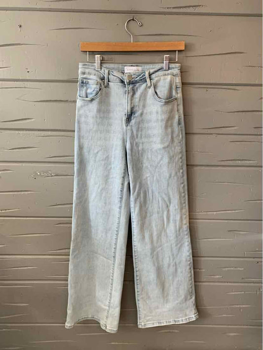 Light blue high-waisted jeans with straight wide legs and front pockets hanging on wooden hanger.