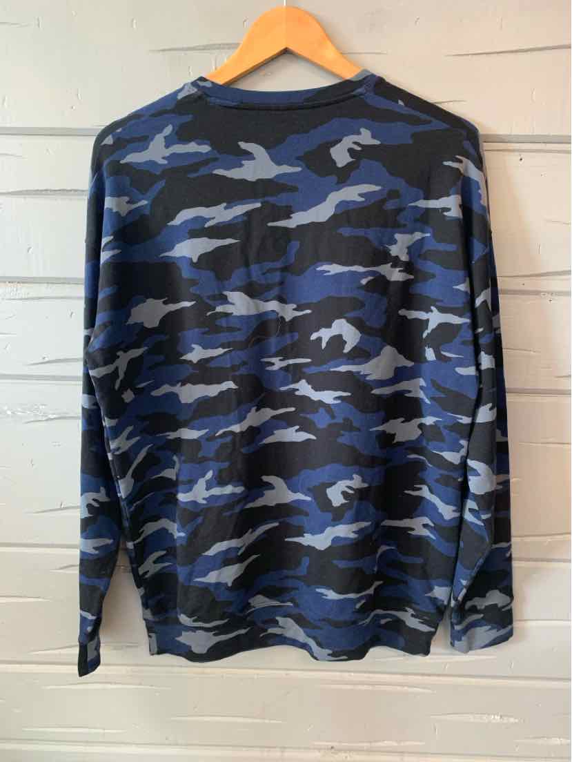 Long-sleeve women's top in blue and black camo print with a relaxed fit on wooden hanger.