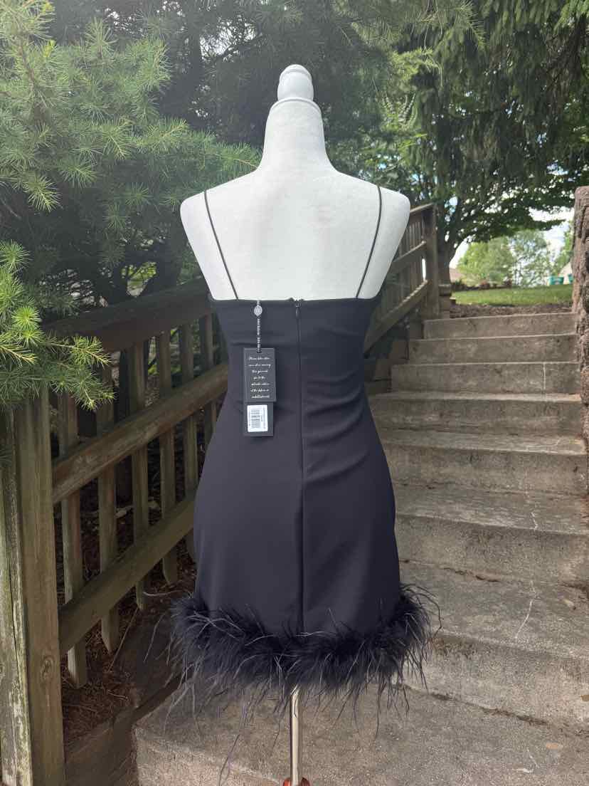Black mini dress with thin straps, fitted silhouette, feather trim hem, and back zipper closure.
