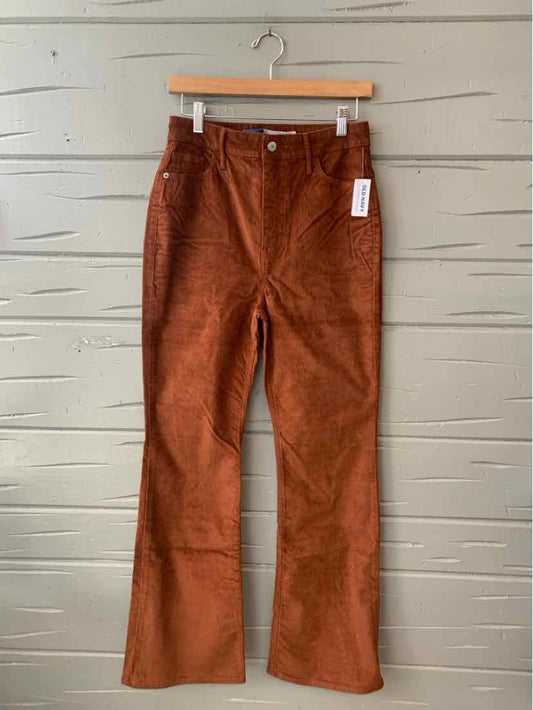 Brown corduroy high-waist pants with front pockets and flared legs size 6 hanging on wooden hanger.