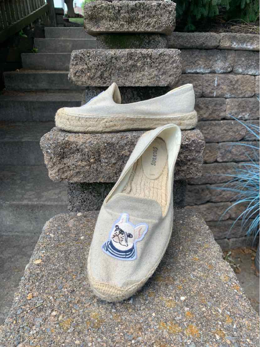 Tan slip-on espadrille with woven jute sole and embroidered cartoon dog patch on top.