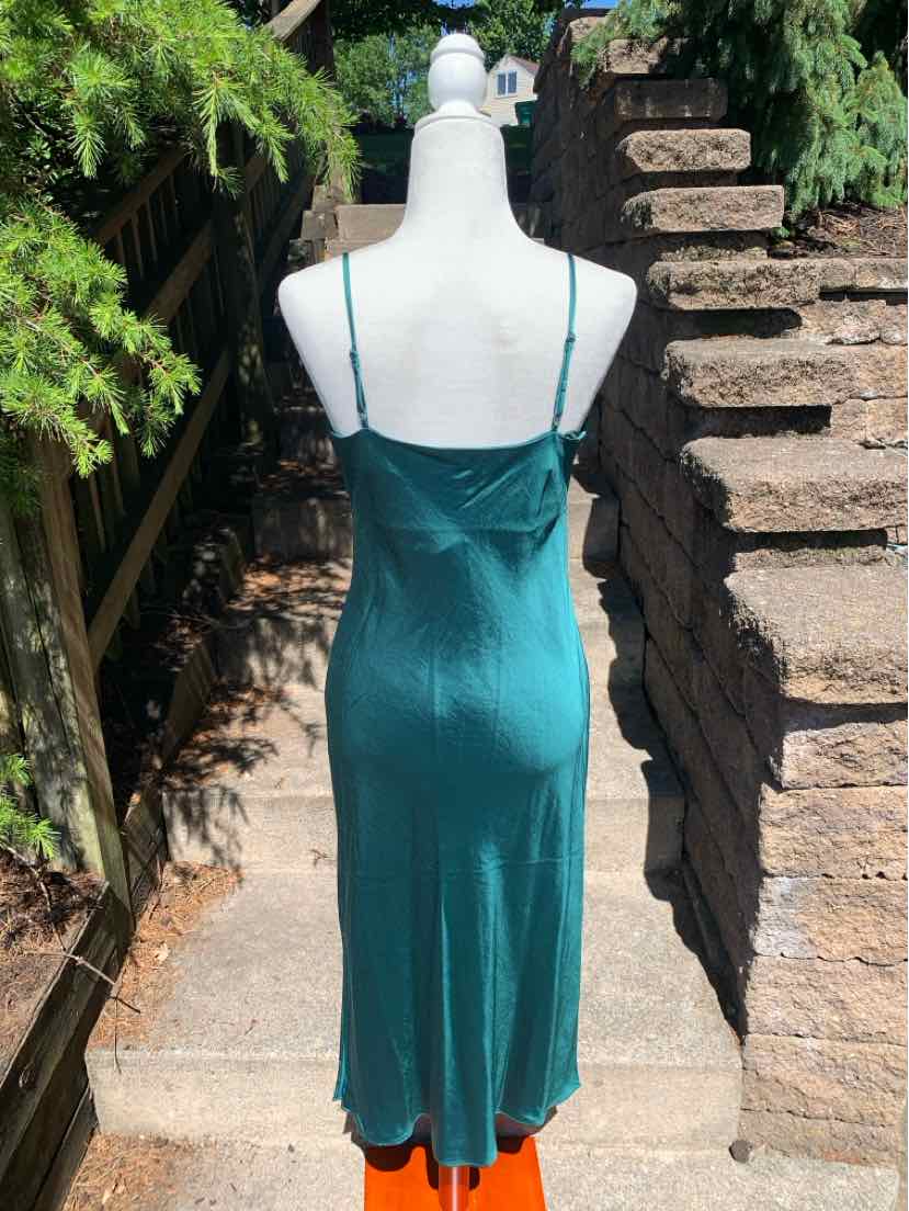 Teal satin slip dress with spaghetti straps and a midi length silhouette on a mannequin outdoors.
