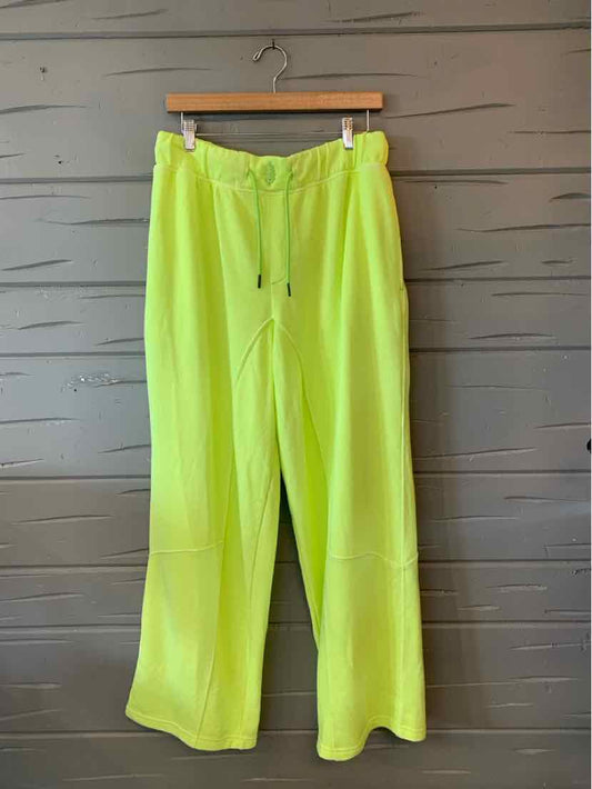 Neon yellow wide-leg pants with drawstring waist and relaxed fit hanging on wooden hanger.