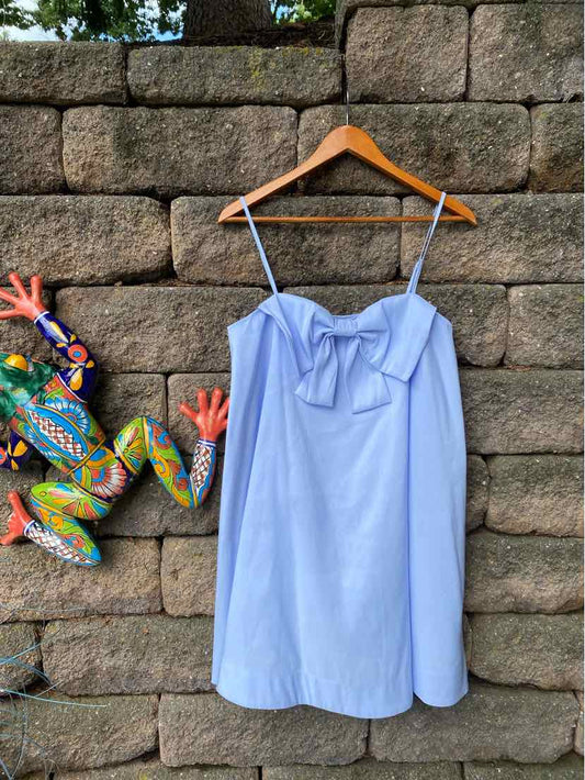 Light blue sleeveless dress with spaghetti straps and a front bow detail, hanging on wooden hanger.