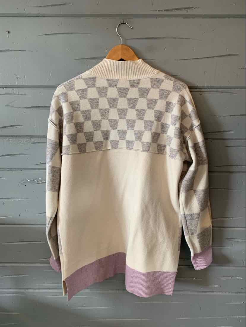 Long cream sweater with gray checkerboard pattern on yoke and sleeves, featuring ribbed lavender hem and cuffs.