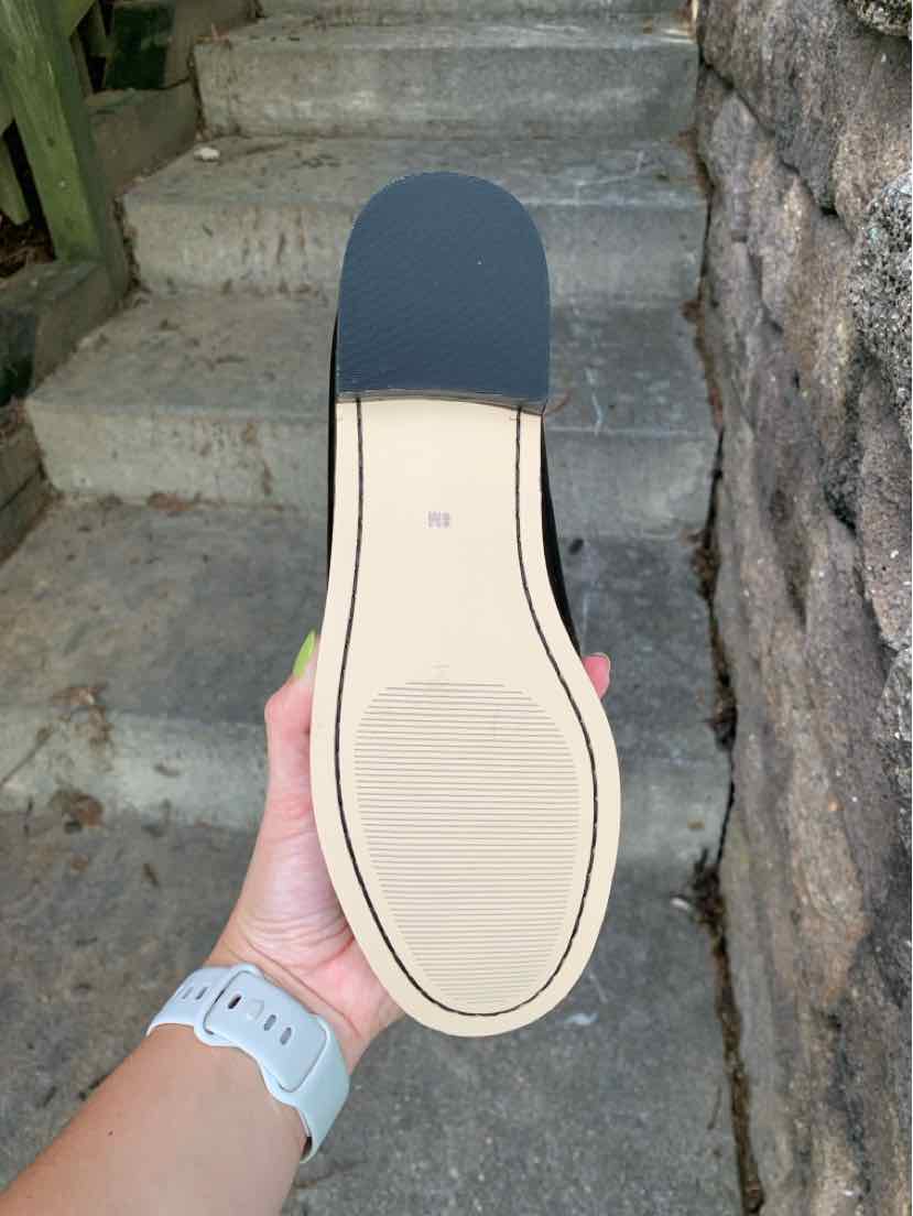 Black flat shoe sole with a beige smooth bottom and a small heel.