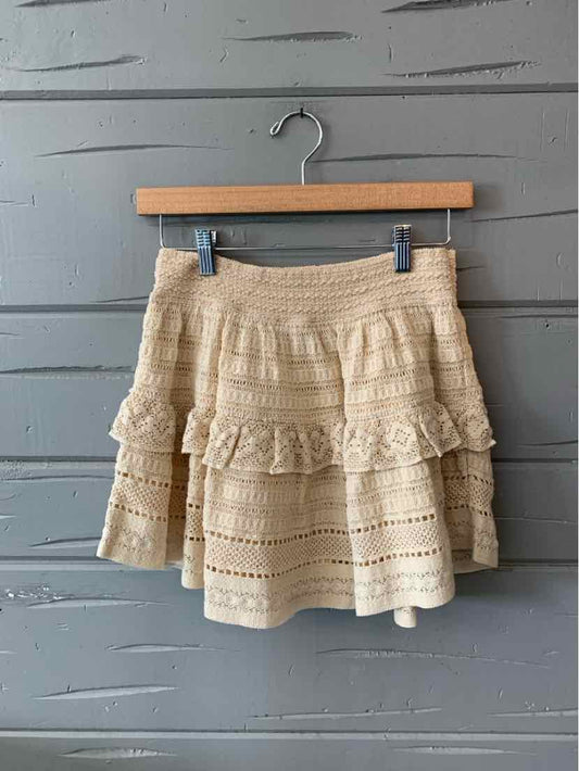 Cream-colored lace mini skirt with layered ruffles and an elastic waistband.