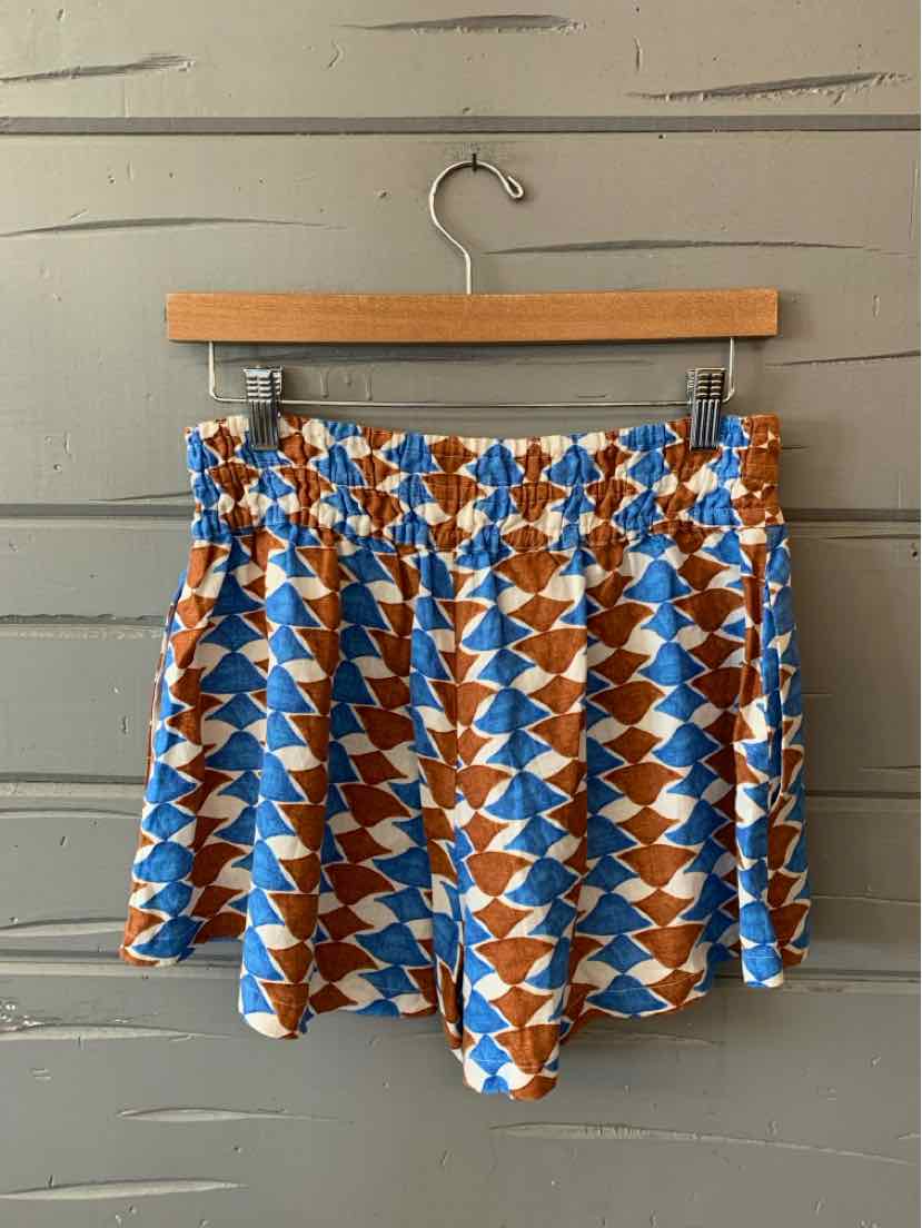 High-waisted shorts with a geometric blue, white, and brown zigzag pattern and a gathered elastic waistband.