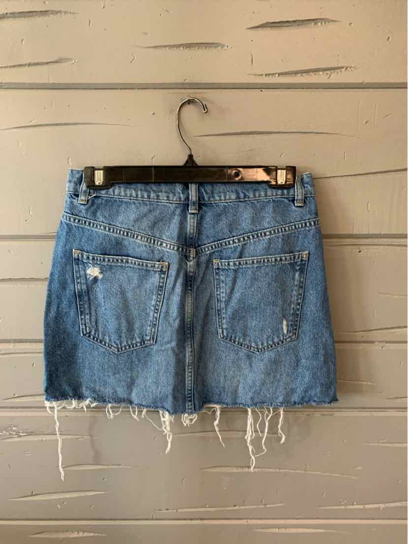 Blue denim mini skirt with frayed hem and two back pockets hanging on black hanger.