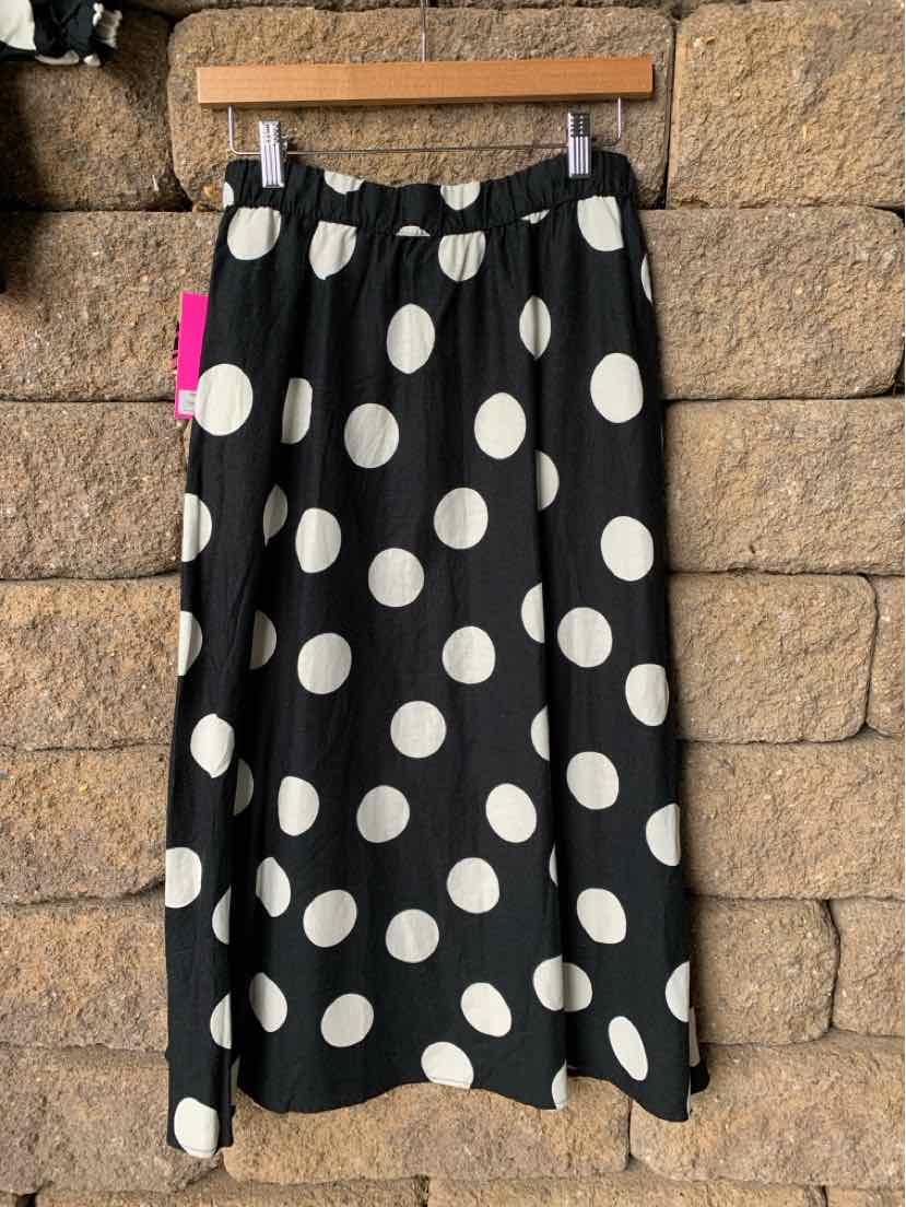 Black midi skirt with large white polka dots, elastic waistband, flowy fabric.