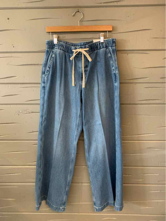 Light blue denim jeans with a white drawstring waistband and relaxed straight legs hanging on a wooden hanger.