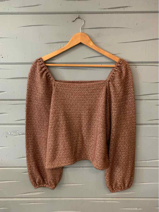 Tan long-sleeve blouse with puffed sleeves and subtle geometric pattern, square neckline.