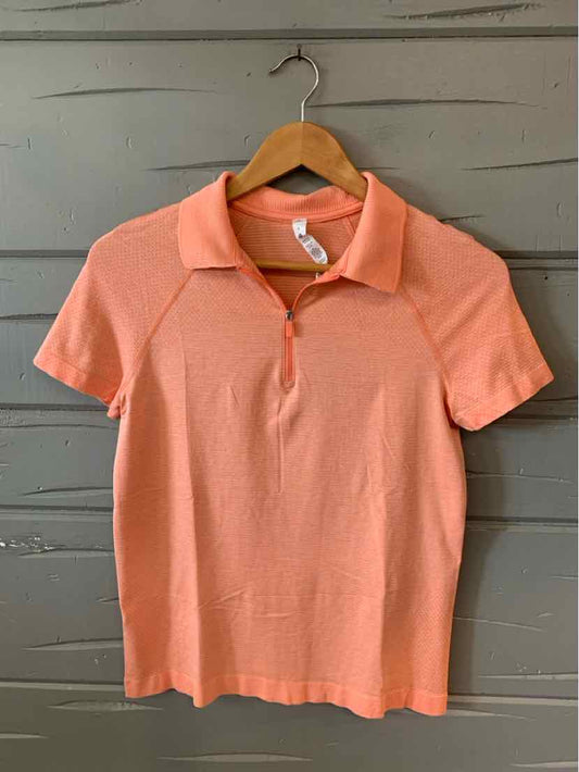 Coral short-sleeve polo shirt with collar and button placket hanging on wooden hanger.
