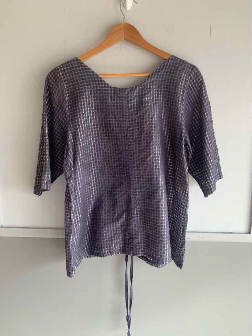 Blue gingham short-sleeve top with round neckline and adjustable waist tie on wooden hanger.