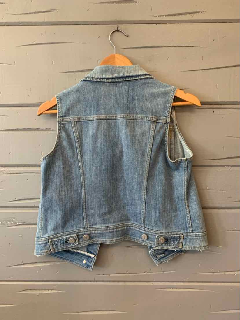 Light blue denim sleeveless vest with button details and a classic collar hanging on wooden hanger against gray wooden.