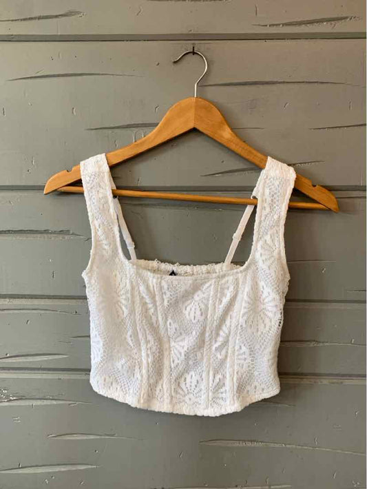 White lace crop top with square neckline and wide straps on wooden hanger.