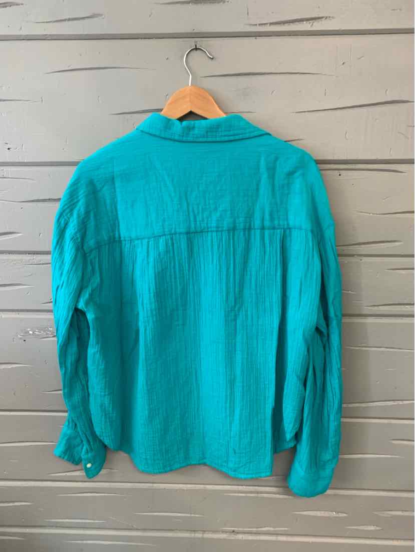 Teal long-sleeve button-up shirt with collar, textured fabric, displayed on wooden hanger against grey wooden wall.