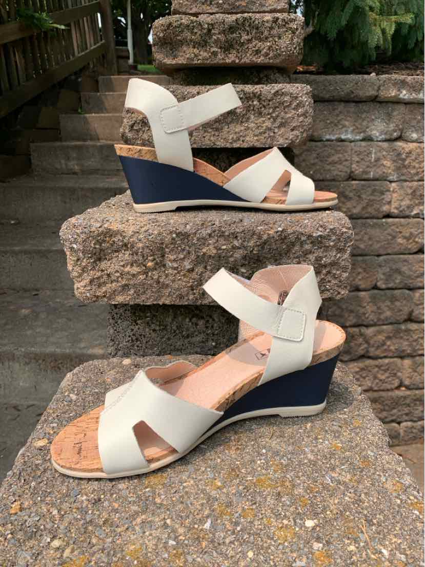 Beige leather wedge sandals with navy blue soles and adjustable ankle straps.